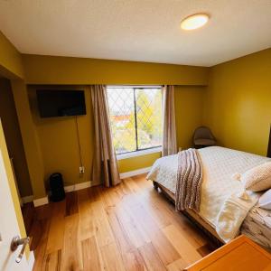 a bedroom with yellow walls and a bed and a window at Oceanside Manor - Ocean View in Qualicum Beach
