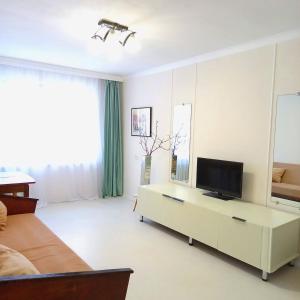 ein Wohnzimmer mit einem Sofa und einem TV in der Unterkunft Квартира трехкомнатная в Орбите 3 на первом этаже in Almaty