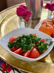 uma taça de morangos numa mesa com rosas em Riad Rossi em Marraquexe
