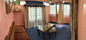 a room with a table and a couch and windows at Movie land group of house boats in Srinagar