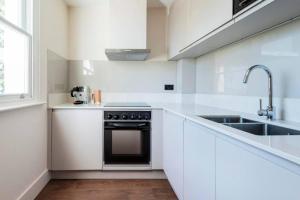 a white kitchen with a stove and a sink at Comfy 2 Bedrooms by Natural History Museum in London