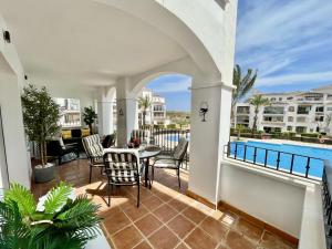 Un balcón con mesa y sillas y una piscina. en Casa Kevin - Hacienda Riquelme Golf Resort, en Sucina 24 fotos más