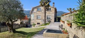 een stenen huis met een palmboom naast een muur bij A casa de Mateu in Pontevedra