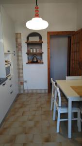 a kitchen with a white table and chairs and a table and a microwave at Sardegnamare&città - La terrazza sul mare in Flumini di Quartu