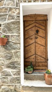 uma porta de madeira numa parede de pedra com vasos de plantas em HÖTEL U SANTA MARIA em Olmeto