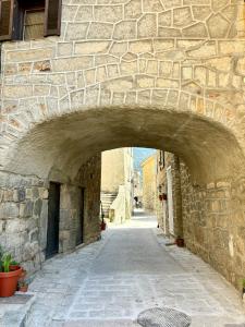 un callejón de piedra con un arco en un edificio de piedra en HÖTEL U SANTA MARIA, en Olmeto