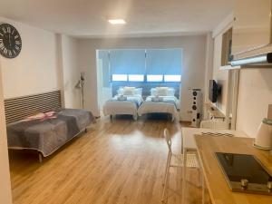 a bedroom with two beds and a kitchen with a window at My Pretty Payma Apartamentos in Benidorm