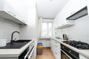 a white kitchen with a sink and a stove at Apartament Na Bajkowej in Busko-Zdrój