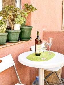 a bottle of wine and two glasses on a table at Venera Apartman in Škaljari
