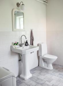 La salle de bains blanche est pourvue d'un lavabo et de toilettes. dans l'établissement Vallby Cottage, à Enköping