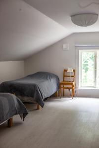 a bedroom with two beds and a chair and a window at Vallby Cottage in Enköping