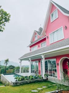uma casa cor-de-rosa com um grande alpendre frontal em Lucia Villa - Melorita Hòa Lạc em Hanói