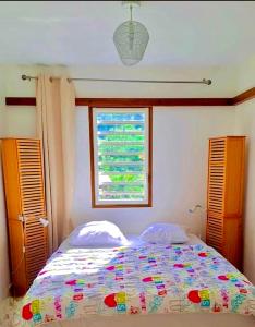 sypialnia z łóżkiem z oknem i kołdrą w obiekcie Bungalow vue mer et montagnes w mieście Pointe-Noire