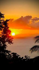 un tramonto su un corpo d'acqua con il sole di Bungalow vue mer et montagnes a Pointe-Noire