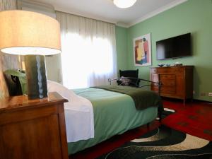 a bedroom with a bed with a lamp and a television at Villa Gisi Guest House in Fiumicino