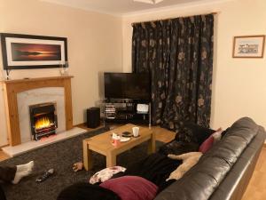 a living room with a couch and a fireplace at Sunbury Aviemore in Aviemore