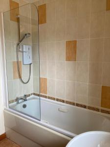 een badkamer met een bad, een toilet en een douche bij Sunbury Aviemore in Aviemore