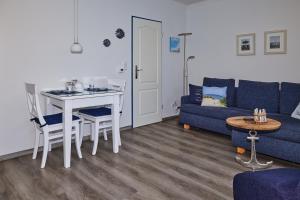 uma sala de estar com um sofá azul e uma mesa em FeWo am Dorfteich em Lemkenhafen auf Fehmarn