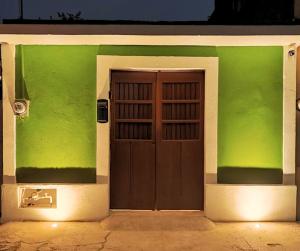 a house with a green wall with a wooden door at Casa Colibri Central Villa with Private Pool and Tub Merida in Mérida