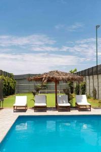 Sunampe的住宿－SOLARIUM CHINCHA Casa de Campo y Playa de 1000mts!，游泳池旁的两把椅子和一把遮阳伞