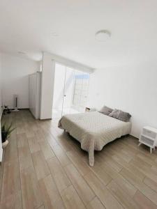 a white bedroom with a bed and a wooden floor at SOLARIUM CHINCHA Casa de Campo y Playa de 1000mts! in Sunampe