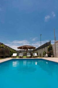 uma grande piscina com duas cadeiras e guarda-sóis em SOLARIUM CHINCHA Casa de Campo y Playa de 1000mts! em Sunampe