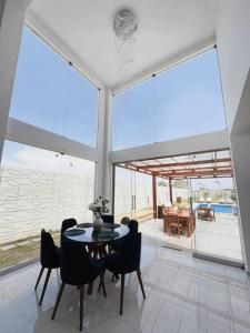 een eetkamer met een tafel, stoelen en ramen bij SOLARIUM CHINCHA Casa de Campo y Playa de 1000mts! in Sunampe