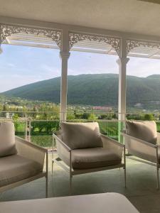 2 sillas en un porche con vistas a la montaña en Gonadze Vineyards Hotel en Ambrolauri