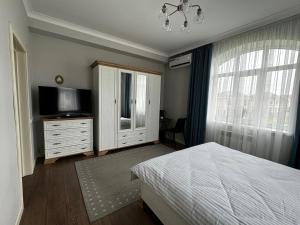a bedroom with a bed and a tv and a dresser at Aikol Guesthouse in Bishkek +32 photos