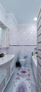 La salle de bains blanche est pourvue de toilettes, d'une baignoire et d'un lavabo. dans l'établissement Жк K7 Family 1-комнатная, à Atyraū