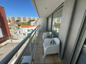 two chairs on a balcony with a view of a city at Apartamento Lux 1882 in Figueira da Foz