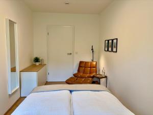 ein Schlafzimmer mit einem Bett und einem Ledersessel in der Unterkunft Leo‘s MUNICH Apartment in München