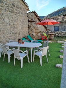 a table and chairs and an umbrella on the grass at Maison de Fernand in Montjay