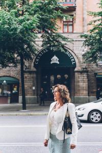 Una donna che cammina per la strada di fronte a un edificio di Crystal Plaza Hotel a Stoccolma