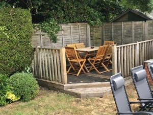 a wooden deck with four chairs and a table at April Cottage, luxurious accommodation for coast and forest with pool & hot tub in Hordle