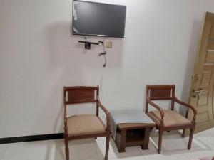 two chairs and a tv on a wall at Murree Apartments in Murree