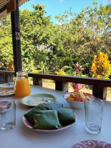 uma mesa com pratos de comida e um copo de sumo de laranja em Rancho Los Duendes em Turrialba