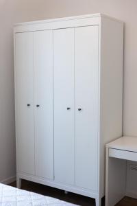 1 dormitorio con armario blanco y armarios blancos en Apartamentai Upės Namai en Šilutė