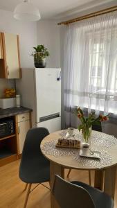 cocina con mesa con sillas y nevera blanca en Apartament 35, en Zamość
