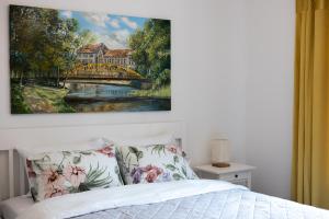 a bedroom with a painting of a bridge over a river at Apartamentai Upės Namai in Šilutė +21 photos
