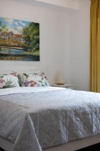 1 dormitorio con 1 cama con una pintura en la pared en Apartamentai Upės Namai en Šilutė
