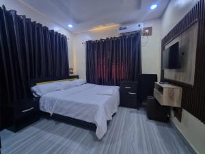 a bedroom with a bed and a flat screen tv at Mirola Apartments in Ilorin