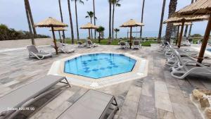 a swimming pool with chairs and umbrellas on a patio at Simos Magic Beach Hotel Apts in Ayia Napa