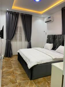 - une chambre avec un grand lit et des rideaux noirs dans l'établissement Sophy Shortlet, à Abuja