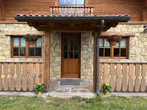 a house with a wooden door and a wooden fence at IL NIDO Chalet in mezzo al verde in Socchieve