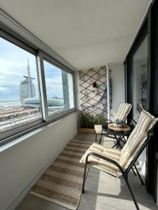 balcón con 2 sillas, mesa y ventanas en Gemütliche Ferienwohnung im Stadtzentrum mit wundervollem Blick, en Bremerhaven