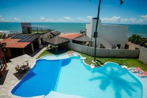 a swimming pool with the ocean in the background at Pousada Un Paso del Mar in Porto De Galinhas