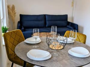 a table with plates and wine glasses on it at White Shell Apartament Hel in Hel