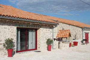 帕爾特奈的住宿－Gite Le marronnier - Parthenay - 10 personnes - Gite à la campagne à 3 kms du centre-ville，前面有两株盆栽植物的砖砌建筑