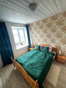 um quarto com uma cama com um edredão verde e uma janela em Tamsalu Wallamaja em Tamsalu